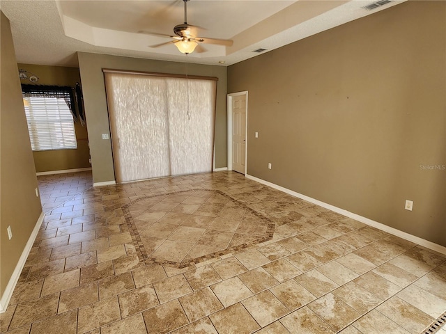 tiled spare room featuring ceiling fan and a raised ceiling