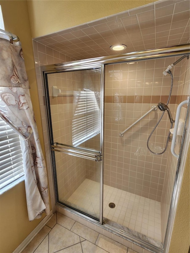 bathroom with a shower with shower door and tile patterned flooring