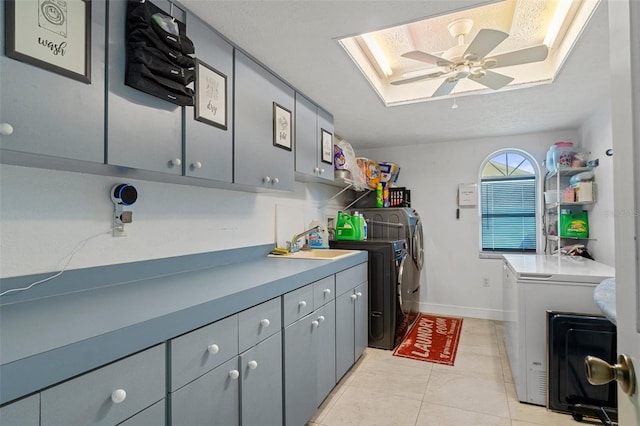 clothes washing area with light tile patterned flooring, a skylight, sink, cabinets, and washer and clothes dryer