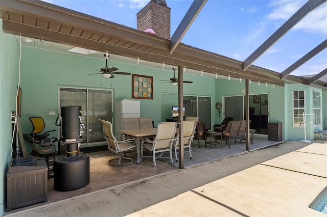 view of patio with ceiling fan and glass enclosure