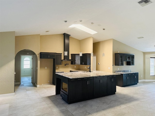 6096 Kinlock Ave, Spring Hill, FL 34608 - kitchen with visible vents, a large island, wall chimney range hood, vaulted ceiling with skylight, and dark cabinetry