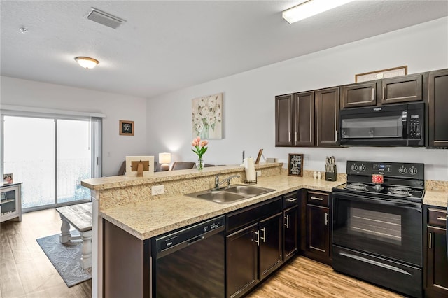 kitchen with black appliances, sink, kitchen peninsula, and light hardwood / wood-style flooring