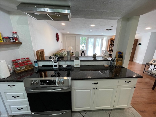 kitchen featuring white cabinets, french doors, dark stone counters, and stainless steel range with electric stovetop