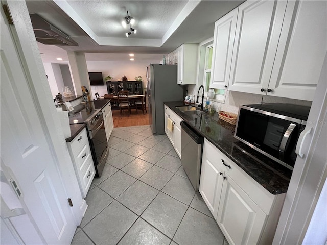 kitchen with a raised ceiling, sink, light tile patterned flooring, stainless steel appliances, and white cabinets