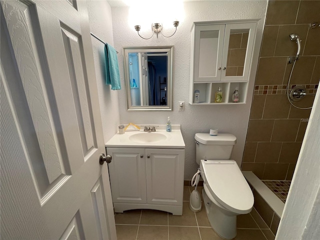 bathroom with toilet, tile patterned floors, vanity, and tiled shower