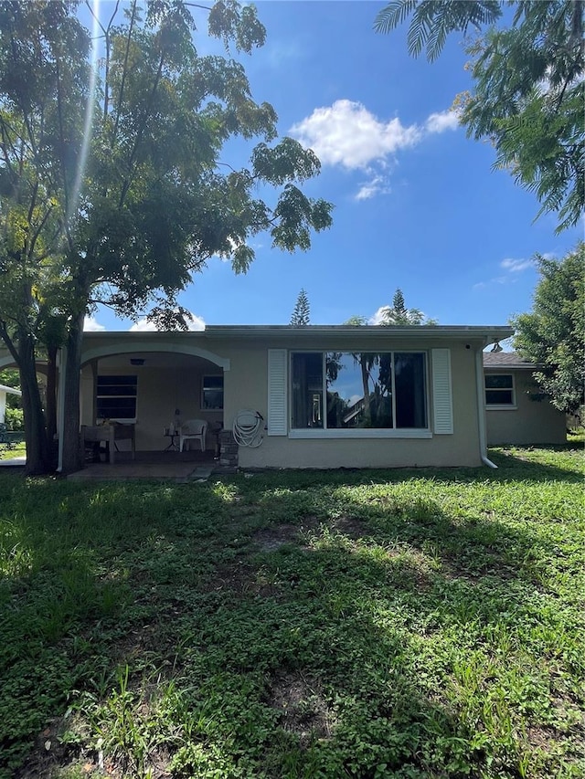 rear view of house with a lawn and a patio