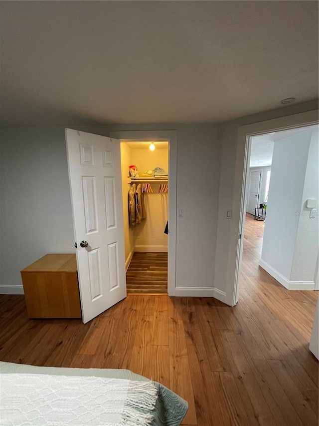 unfurnished bedroom with a spacious closet, hardwood / wood-style floors, and a closet