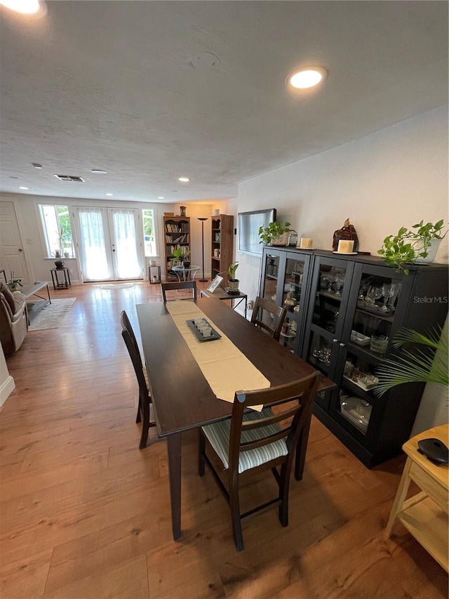 dining room with french doors and light hardwood / wood-style flooring