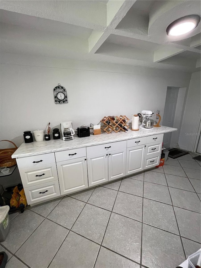 kitchen with light tile patterned floors, coffered ceiling, and white cabinetry