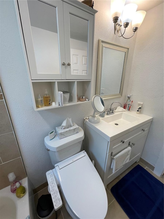 bathroom with tile patterned floors, vanity, toilet, a bath, and a notable chandelier