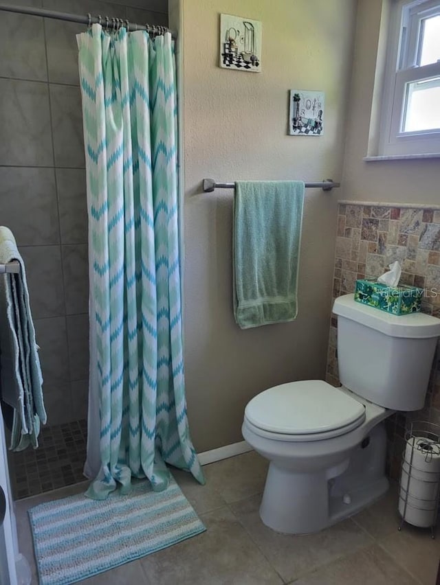 bathroom with a stall shower, tile walls, toilet, and tile patterned floors