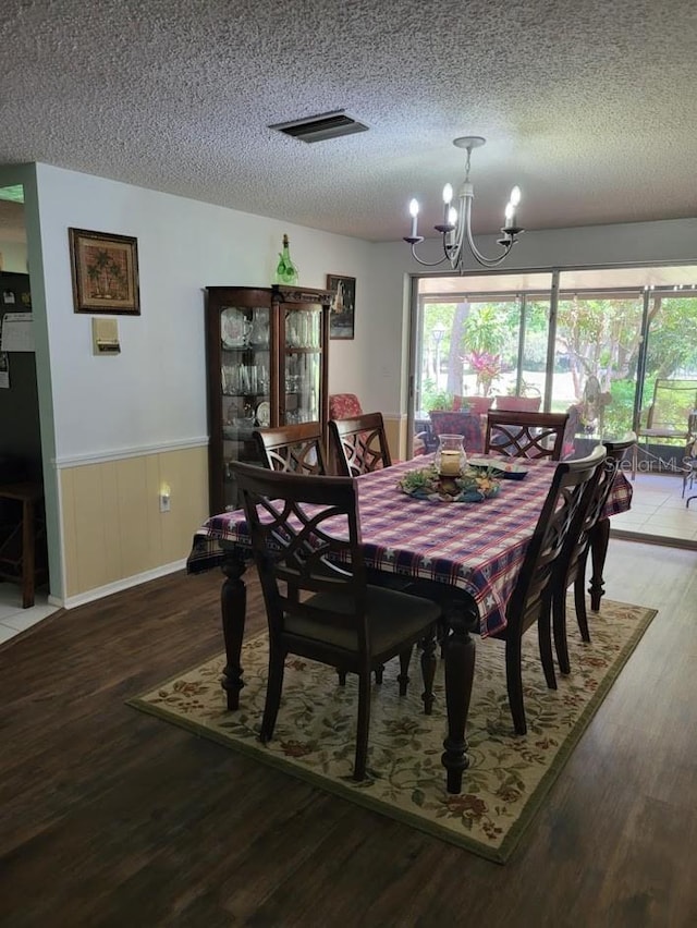 dining area with hardwood / wood-style floors, a notable chandelier, and a textured ceiling