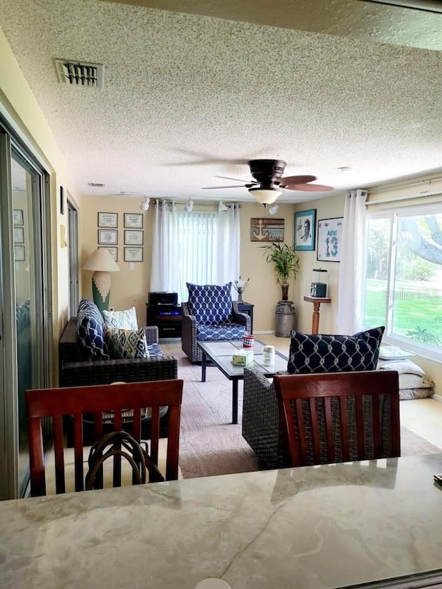 living room featuring ceiling fan and a textured ceiling