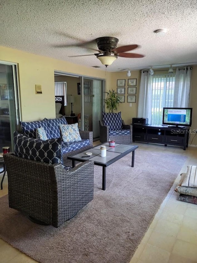 living area featuring a ceiling fan and a textured ceiling