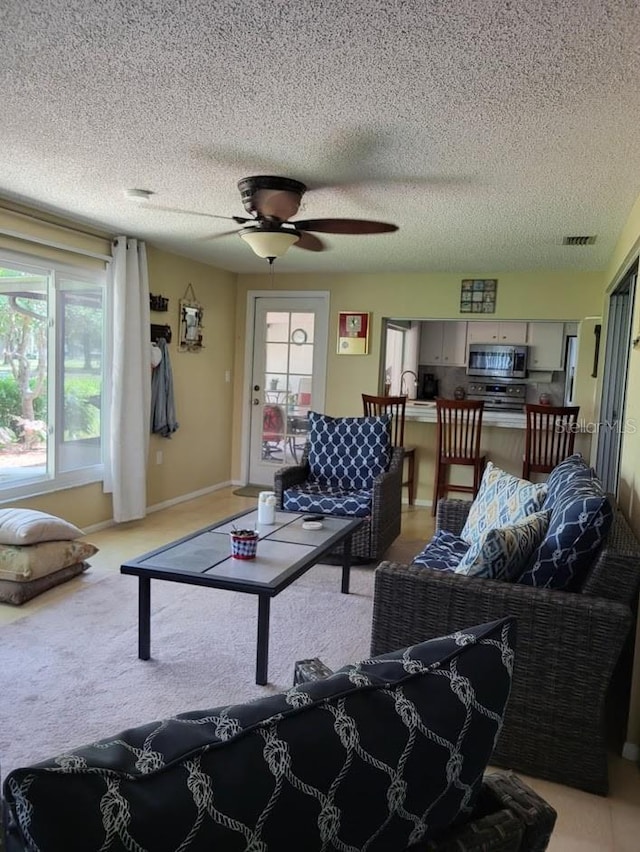 carpeted living room with a textured ceiling, a wealth of natural light, and ceiling fan