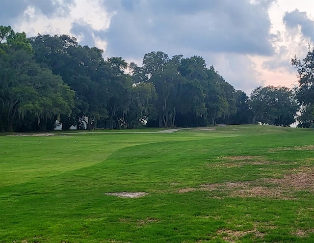 view of home's community with view of golf course and a lawn