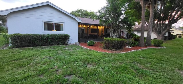 rear view of property featuring a lawn and stucco siding