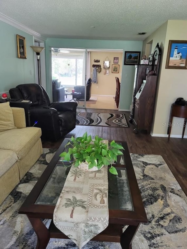 living room with dark wood-style floors, visible vents, baseboards, and a textured ceiling