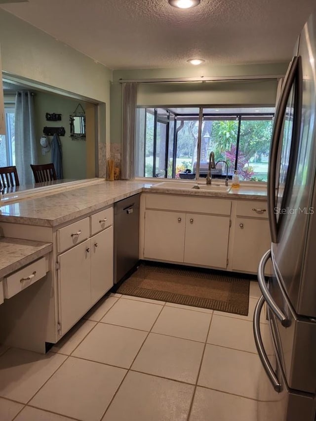 kitchen with black dishwasher, white cabinets, light countertops, and freestanding refrigerator