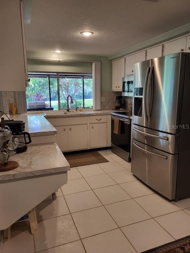 kitchen featuring tasteful backsplash, stainless steel appliances, light countertops, white cabinetry, and a sink