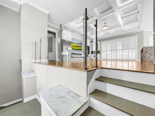 staircase featuring crown molding, coffered ceiling, and a fireplace