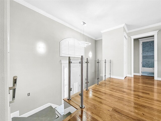 hall with ornamental molding, hardwood / wood-style floors, and an inviting chandelier