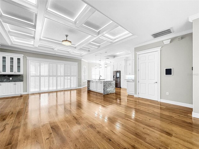 unfurnished living room featuring ornamental molding, coffered ceiling, and hardwood / wood-style floors