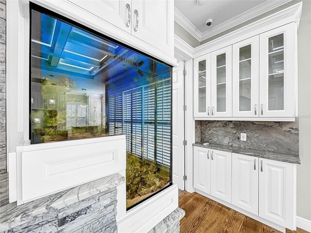 bar featuring white cabinetry, dark stone countertops, ornamental molding, dark hardwood / wood-style floors, and backsplash