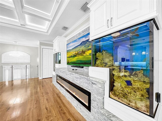 kitchen featuring crown molding, white cabinetry, coffered ceiling, light stone countertops, and light hardwood / wood-style floors