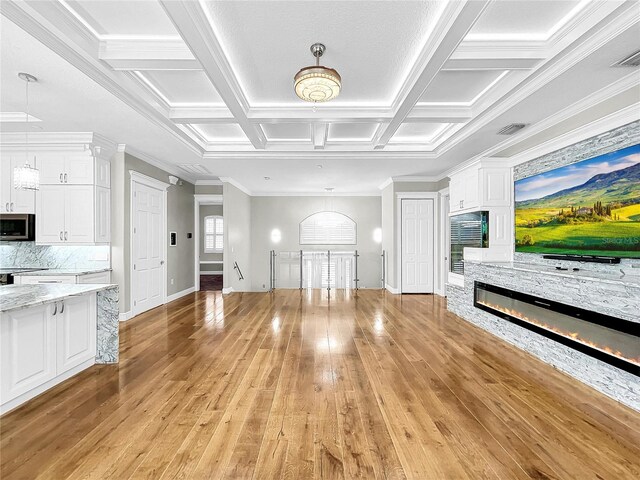 unfurnished living room with coffered ceiling, ornamental molding, a fireplace, and light hardwood / wood-style floors