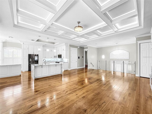 unfurnished living room featuring beamed ceiling, coffered ceiling, sink, and light hardwood / wood-style floors