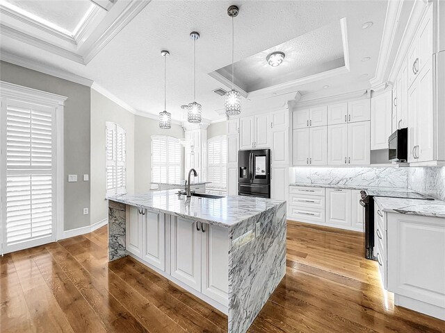 kitchen featuring a large island with sink, stainless steel fridge with ice dispenser, white cabinets, and a tray ceiling