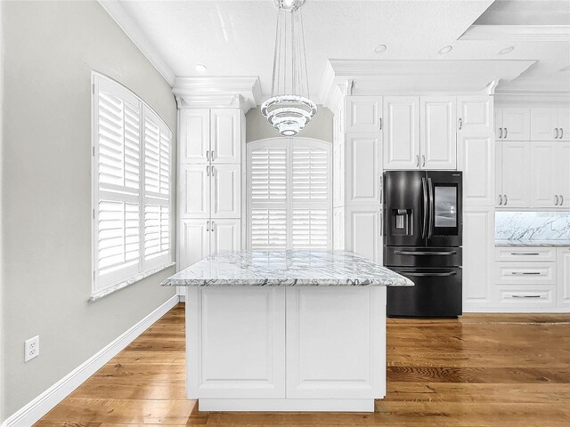 kitchen with pendant lighting, white cabinets, crown molding, stainless steel refrigerator with ice dispenser, and light stone countertops