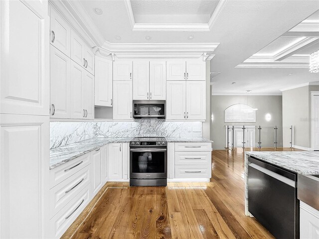 kitchen with white cabinetry, ornamental molding, stainless steel appliances, light stone countertops, and light hardwood / wood-style floors