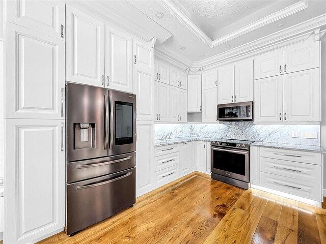 kitchen featuring white cabinetry, light stone counters, light hardwood / wood-style flooring, and stainless steel appliances