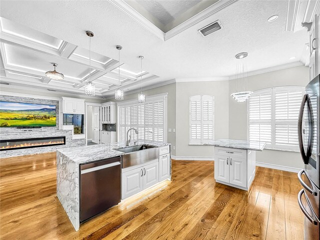 kitchen featuring stainless steel appliances, white cabinetry, sink, and a center island with sink