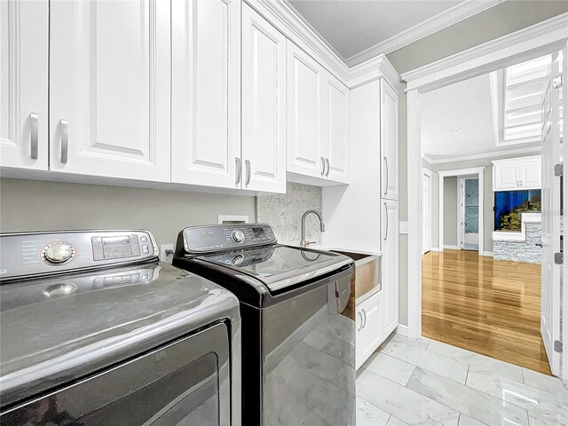 laundry area with ornamental molding, washing machine and dryer, and cabinets