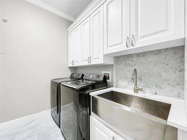 laundry room with cabinets, ornamental molding, washer and clothes dryer, and sink