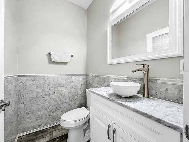 bathroom with vanity, toilet, and tile walls