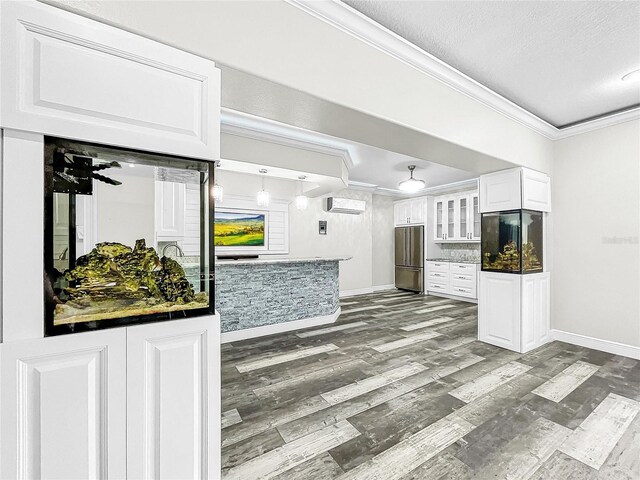 kitchen with crown molding, hardwood / wood-style flooring, refrigerator, and white cabinets