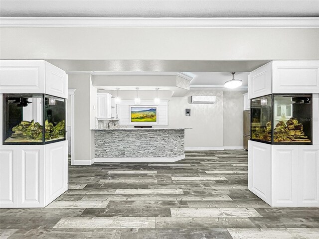 kitchen featuring ornamental molding, decorative light fixtures, a wall mounted air conditioner, and white cabinets