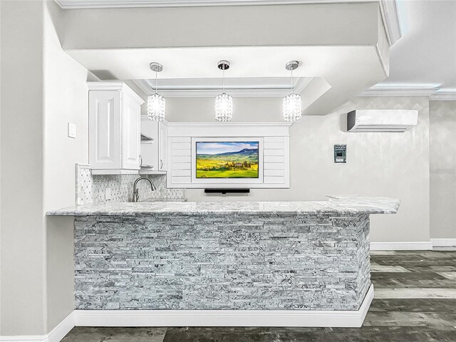 bar featuring crown molding, a wall mounted air conditioner, decorative light fixtures, and white cabinets