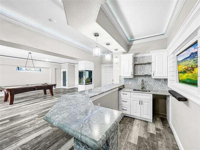 kitchen with white cabinetry, sink, crown molding, and light stone counters