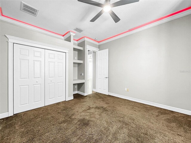 unfurnished bedroom with ceiling fan, dark colored carpet, ornamental molding, a textured ceiling, and a closet