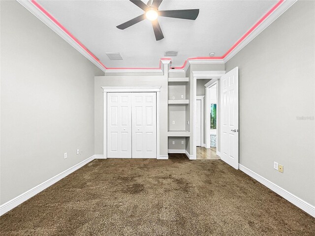 unfurnished bedroom with crown molding, dark carpet, a closet, and ceiling fan