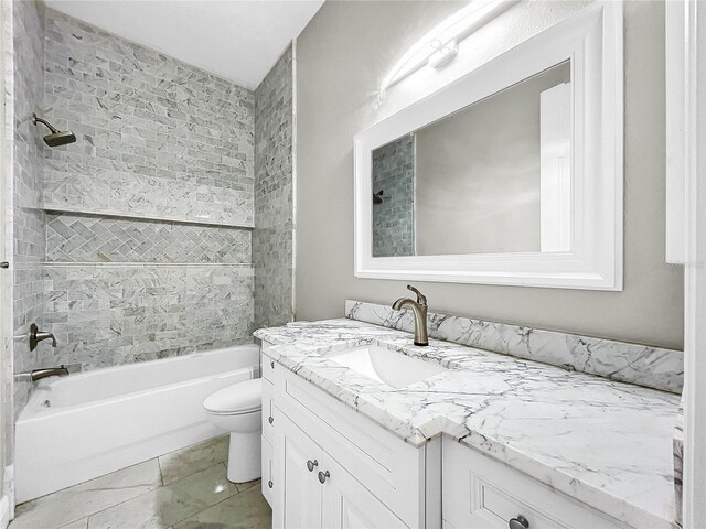 full bathroom with tiled shower / bath, vanity, and toilet