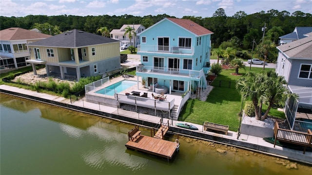 back of house featuring a water view, a balcony, a lawn, and a patio area