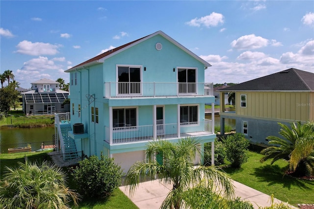 back of property with a water view, a balcony, and a yard