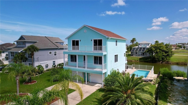 back of property with a garage, a balcony, a water view, and a lawn