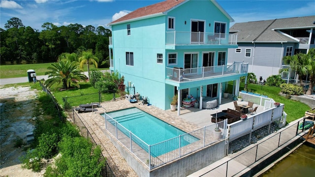 back of house with a fenced in pool, a yard, a patio, and a balcony